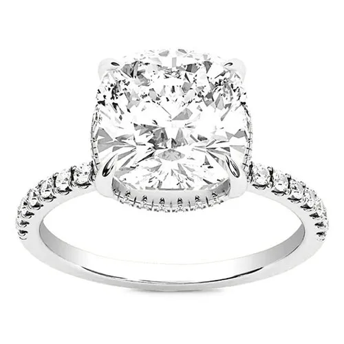 A silver-toned ring featuring a large cushion-cut diamond set in a four-prong setting, with a band adorned with smaller round diamonds.