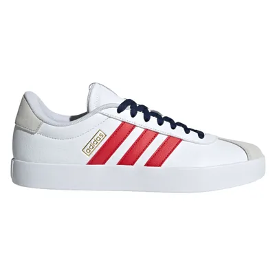 An Adidas sneaker featuring a white body, red stripes, navy blue laces, and a touch of suede on the heel.