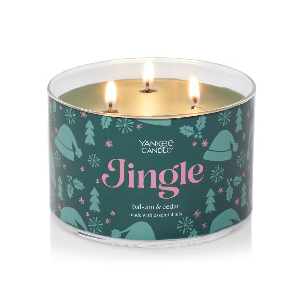 A three-wick candle with a teal label featuring snowflakes and the text \“Yankee Candle Jingle balsam & cedar\“ indicating the scent.