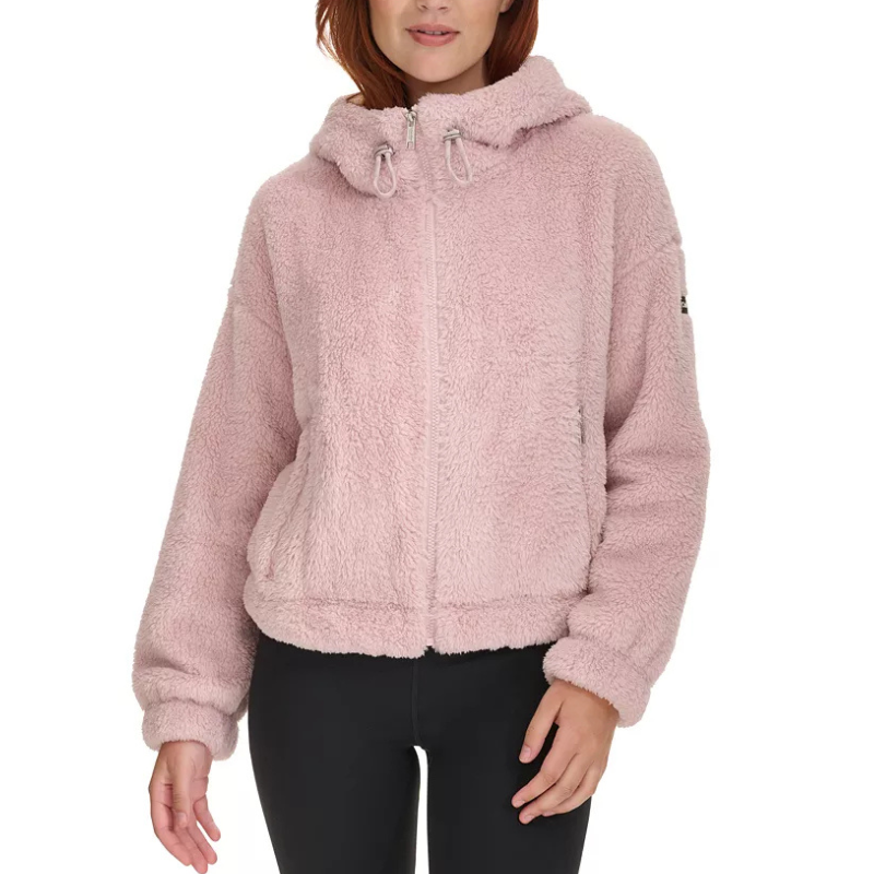 A pink Calvin Klein Sherpa Jacket with a fuzzy texture, featuring a hood with drawstrings and a front zipper. The jacket has long sleeves and an elasticized hem, designed for a cozy fit.