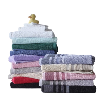Stacks of folded towels in various colors with a rubber duck on top.