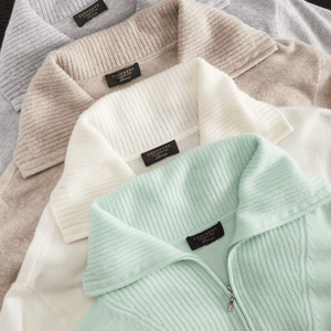 Four cashmere sweaters in pastel gray, beige, white, and mint colors are displayed with ribbed collars and labeled \“Cashmere.\“