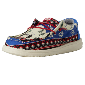 Hey Dude Wally Holiday Cheers Shoes feature a festive design with patterns of reindeer, trees, and snowflakes in blue, red, and cream colors, complemented by red laces and a cushioned white sole.