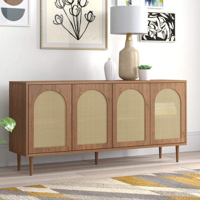 A mid-century modern style sideboard with arched cane doors, finished in wood, featuring tapered legs and gold-toned hardware. The design includes ample storage space within.