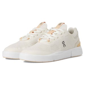 On Women's Roger Spin 2 Sneakers feature a sleek, low-profile design in white with beige accents, a breathable mesh upper, and cushioned sole for comfort.
