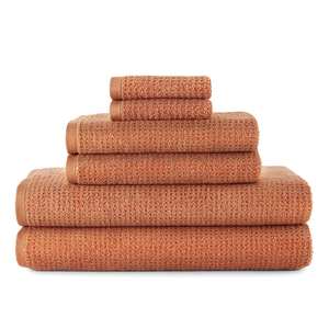 Stack of terracotta-colored towels, including bath towels, hand towels, and washcloths, neatly arranged by size.