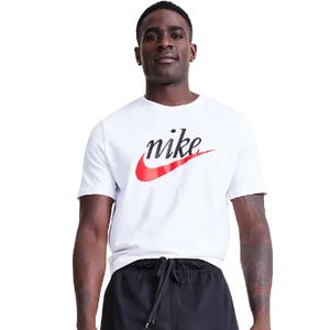A man is wearing a white Nike tee with a red swoosh and Nike script logo across the chest, paired with black shorts.