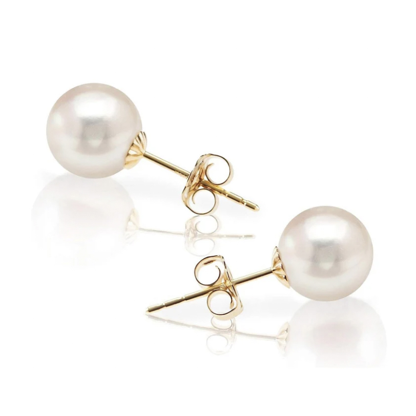 A pair of pearl earrings with gold posts and backs on a reflective surface.