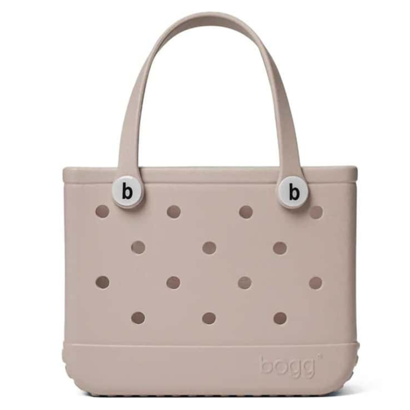 A beige Bogg Bag with perforated design, featuring two handles and round button accents with the letter \“b\“.