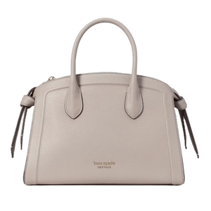 A taupe Kate Spade Zip-Top Leather Satchel with dual handles, pebbled texture, and side tassel details. It features the brand's logo on the front, offering a classic and elegant look.