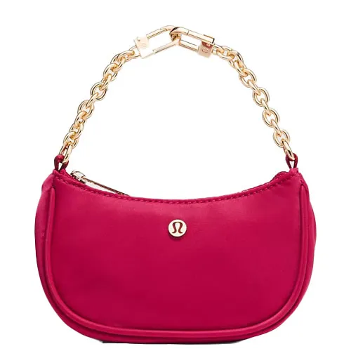A small pink handbag with a gold chain strap, featuring a logo on the front.
