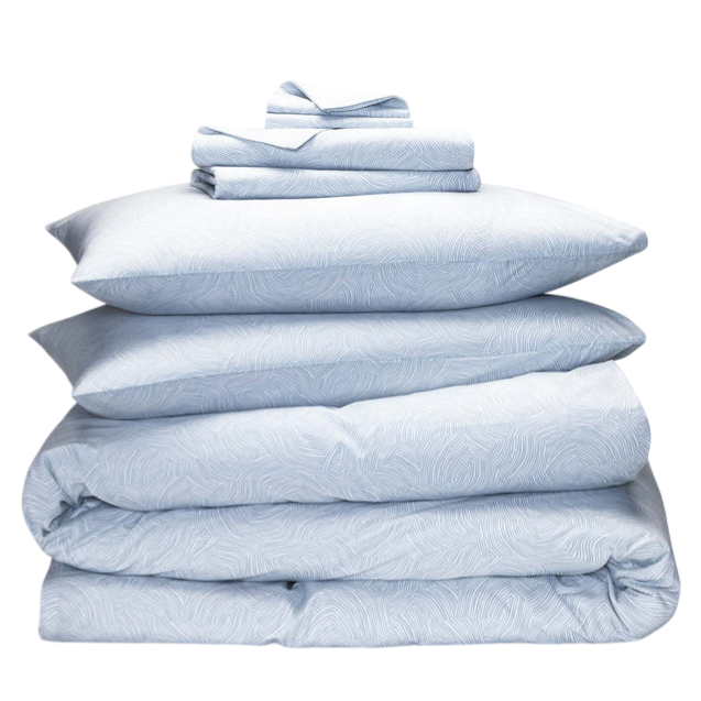 A neatly stacked blue bedding set featuring a duvet cover, sheet set, and multiple pillowcases with a subtle line pattern.
