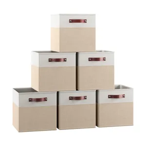 Set of six beige and white fabric storage bins with brown handles, stacked in a pyramid formation.