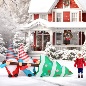 A 7-foot inflatable holiday decoration featuring two gnomes in red and blue outfits carrying a large, stylized Christmas tree with colorful polka dots, set in a snowy winter scene in front of a festive red house.