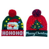 Two festive winter hats with pom-poms; one features Santa with \“HO HO HO\“ and the other shows a Christmas tree with \“Merry Christmas.\“ Both include colorful LED lights.