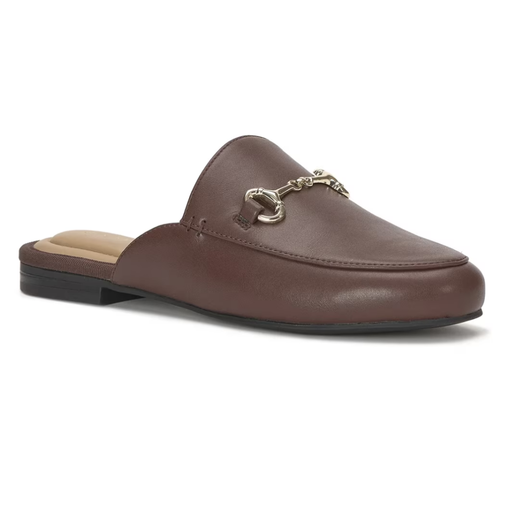 A brown leather mule slipper featuring a classic loafer design with metallic hardware across the front, and a flat heel suitable for casual wear.