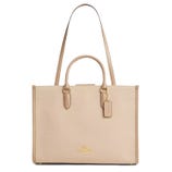 A beige Coach bag with dual handles, a long shoulder strap, gold hardware, and a Coach tag.