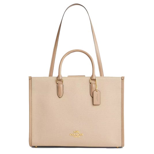 A beige Coach bag with dual handles, a long shoulder strap, gold hardware, and a Coach tag.