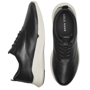 Black leather sneakers with white soles, featuring a lace-up design and \“Cole Haan\“ visible on the insole.