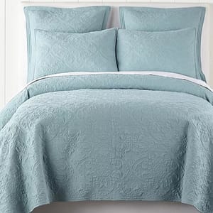 A teal-colored quilt set featuring subtle embossed patterns, including a quilt and matching pillow shams.