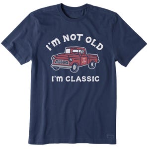 A navy blue T-shirt features a red classic truck illustration with the text \“I'm NOT OLD, I'M CLASSIC.\“ The phrase \“LIFE IS GOOD\“ is written on the truck's door.