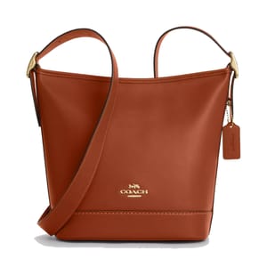 A brown Coach leather bucket bag with a gold logo, tag, and adjustable strap.