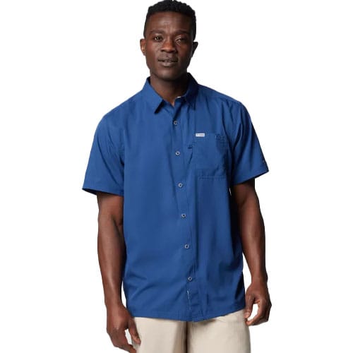 A man is wearing a blue, short-sleeve button-up shirt with a chest pocket, paired with beige pants.