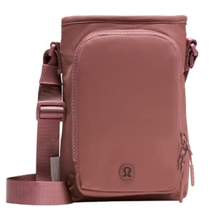 A pink crossbody bag with an adjustable strap and front pocket featuring the Lululemon logo.