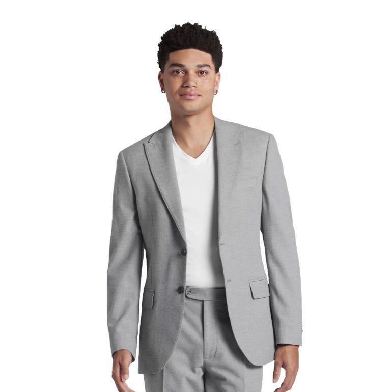 A person wearing a light gray suit with a matching jacket and trousers, paired with a white v-neck t-shirt.