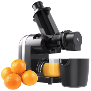 A masticating juicer is shown alongside a small batch of whole oranges and a glass filled with fresh orange juice.