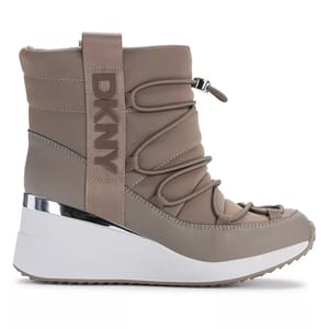 A taupe DKNY women's wedge boot features a padded design with crisscross laces, a metallic accent, and a thick white sole for a stylish, modern look.