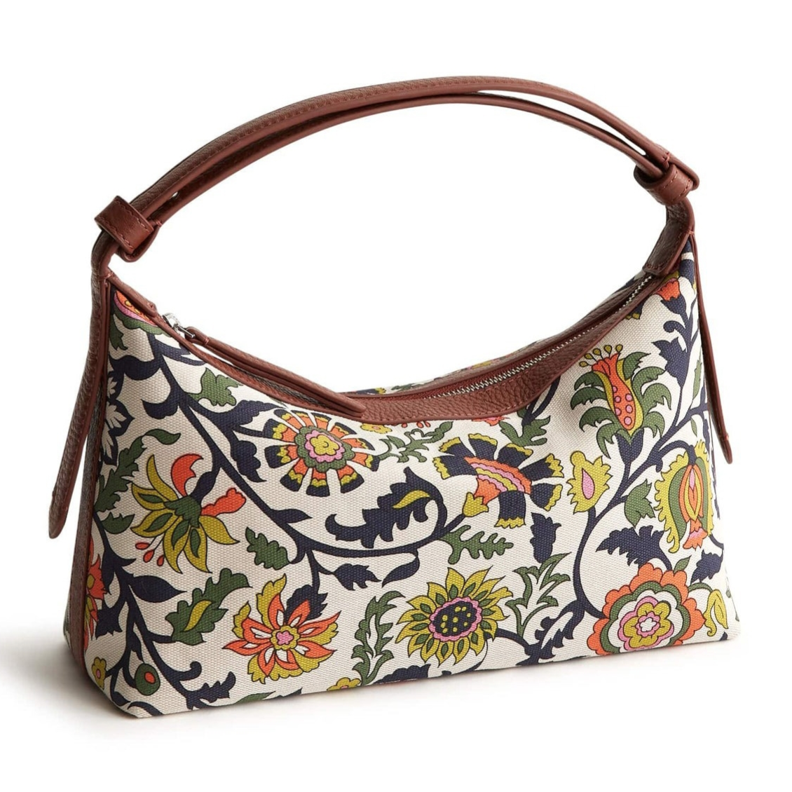 A handbag with a curved brown handle features a colorful floral pattern on a white background, incorporating yellow, red, green, and black designs.