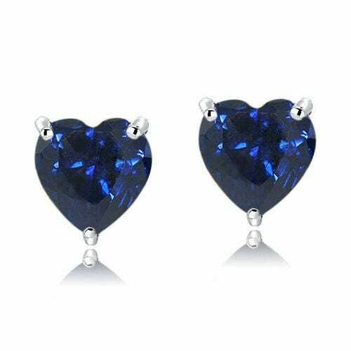 A pair of heart-shaped sapphire stud earrings set in a prong setting with a reflective surface beneath.