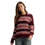 A woman is wearing a striped sweater in shades of red and pink with long sleeves, paired with jeans.