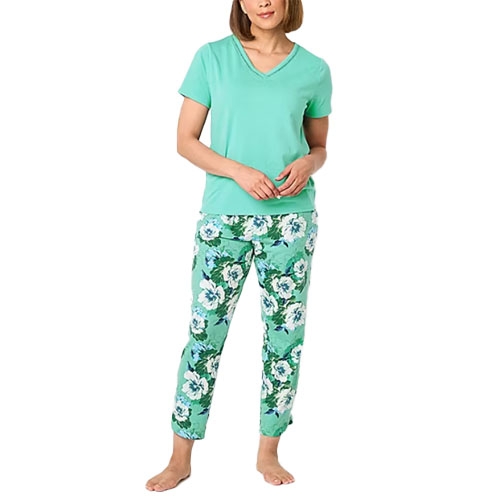 A woman is wearing a green V-neck t-shirt paired with floral print pants featuring green and white flowers.