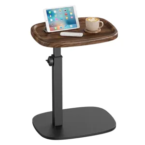 Adjustable-height wooden side table with a rectangular top, holding a tablet, remote control, and a cup of coffee; features a sturdy black base.