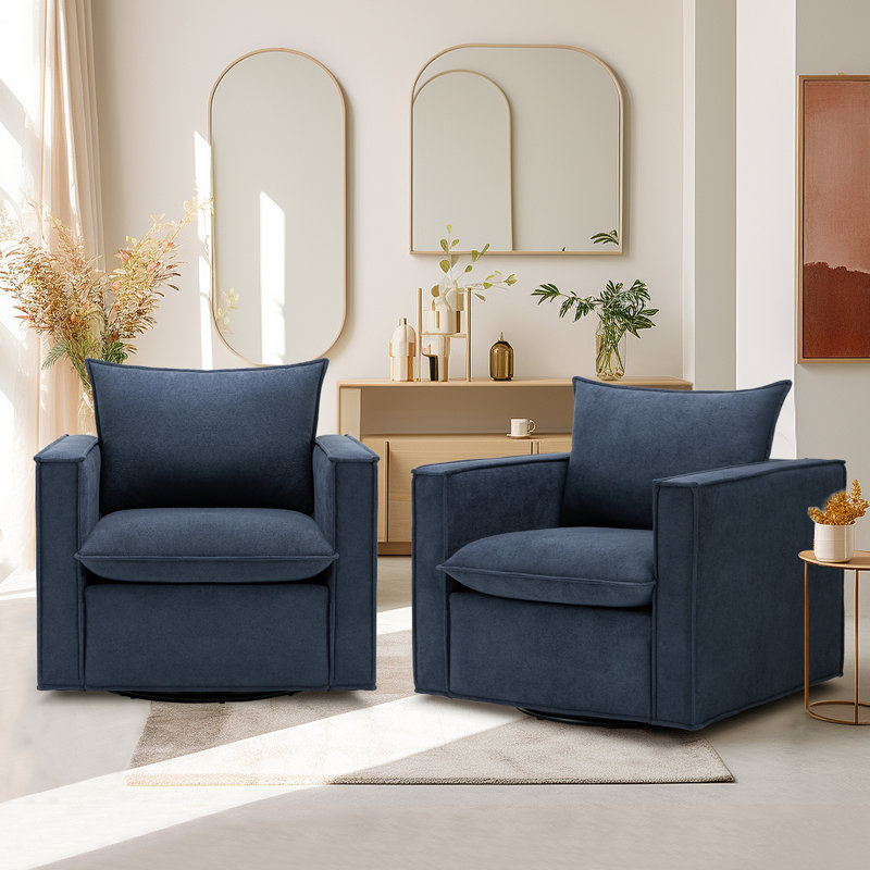 Two navy blue armchairs are placed on a light-colored rug in front of a wooden console with decorative plants and mirrors on the wall.