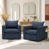 Two navy blue armchairs are placed on a light-colored rug in front of a wooden console with decorative plants and mirrors on the wall.