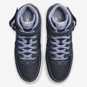 A pair of Nike Air Force 1 sneakers in a navy blue colorway with white detailing and laces.