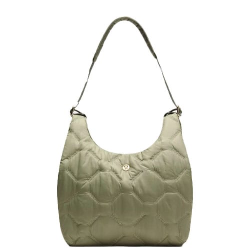 A quilted shoulder bag in a light olive color with a single strap and a gold button detail in the center.