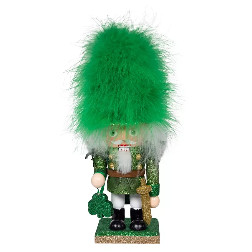 Kurt Adler 9\“ Hollywood Irish Nutcracker features a green outfit adorned with glitter, a large fluffy green hat, and holds a shamrock-shaped ornament in one hand.