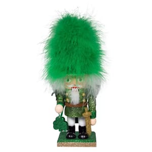 Kurt Adler 9\“ Hollywood Irish Nutcracker features a green outfit adorned with glitter, a large fluffy green hat, and holds a shamrock-shaped ornament in one hand.