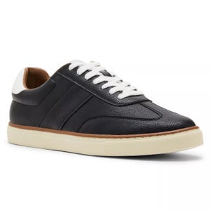 A low-top sneaker with textured black leather upper, white laces, a padded collar, and a cream rubber sole.