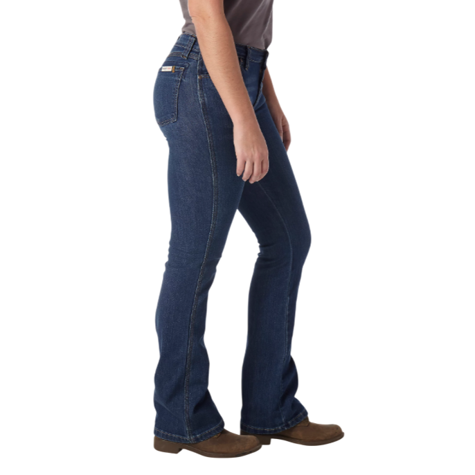 Dark blue bootcut jeans and brown shoes are shown on a person standing sideways.