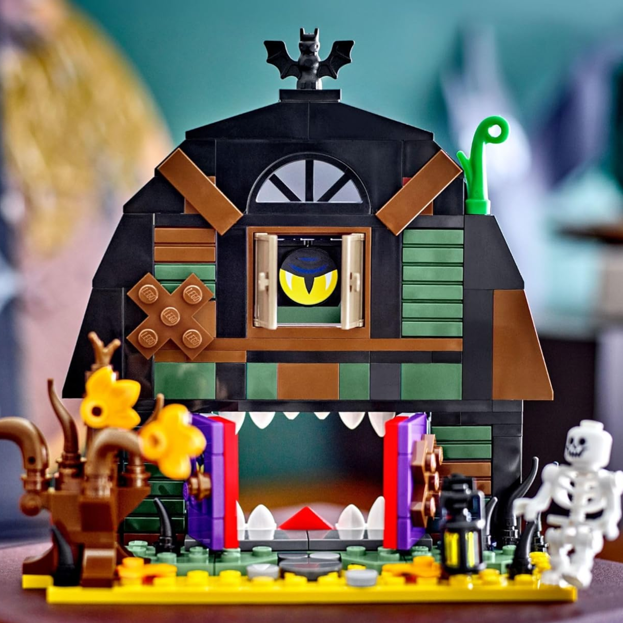 A LEGO set with a Halloween-themed haunted house features details like hidden teeth, a bat, and a skeleton figure, enhancing its spooky appearance.
