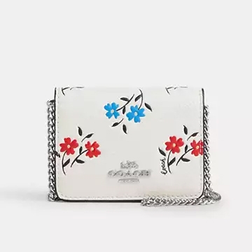 A white floral crossbody bag with a chain strap and a silver clasp.