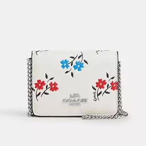A white floral crossbody bag with a chain strap and a silver clasp.