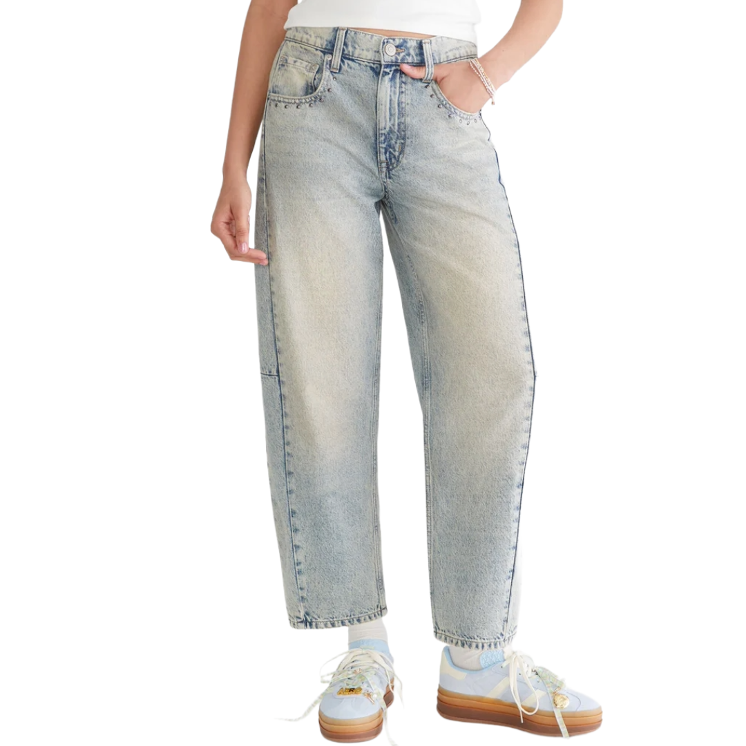 A person wearing light-wash, high-rise straight-leg jeans with a relaxed fit, paired with pastel sneakers featuring a thick sole.