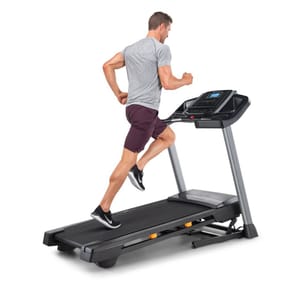 A man runs on a NordicTrack treadmill with a sleek design, featuring a digital console for tracking workouts. The treadmill has a sturdy frame and cushioned running surface for comfort.