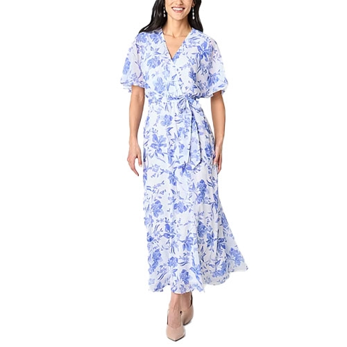 A woman models a flowing sheer blue and white floral wrap blouse maxi dress with short flutter sleeves, a v-neckline, and an elastic waistband with a matching tie belt, paired with pointed toe heeled shoes.